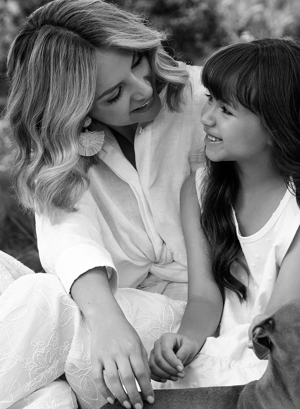 Foto en plano detalle de mujer usando camisa blanca junto a su hija