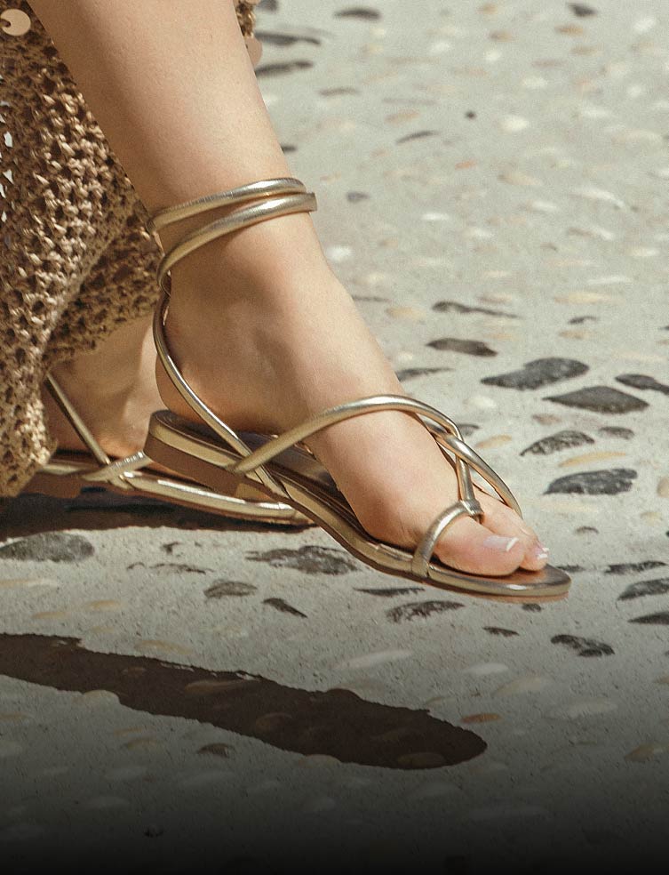 Fotografía de sandalias planas para mujer de tiras en color dorado.