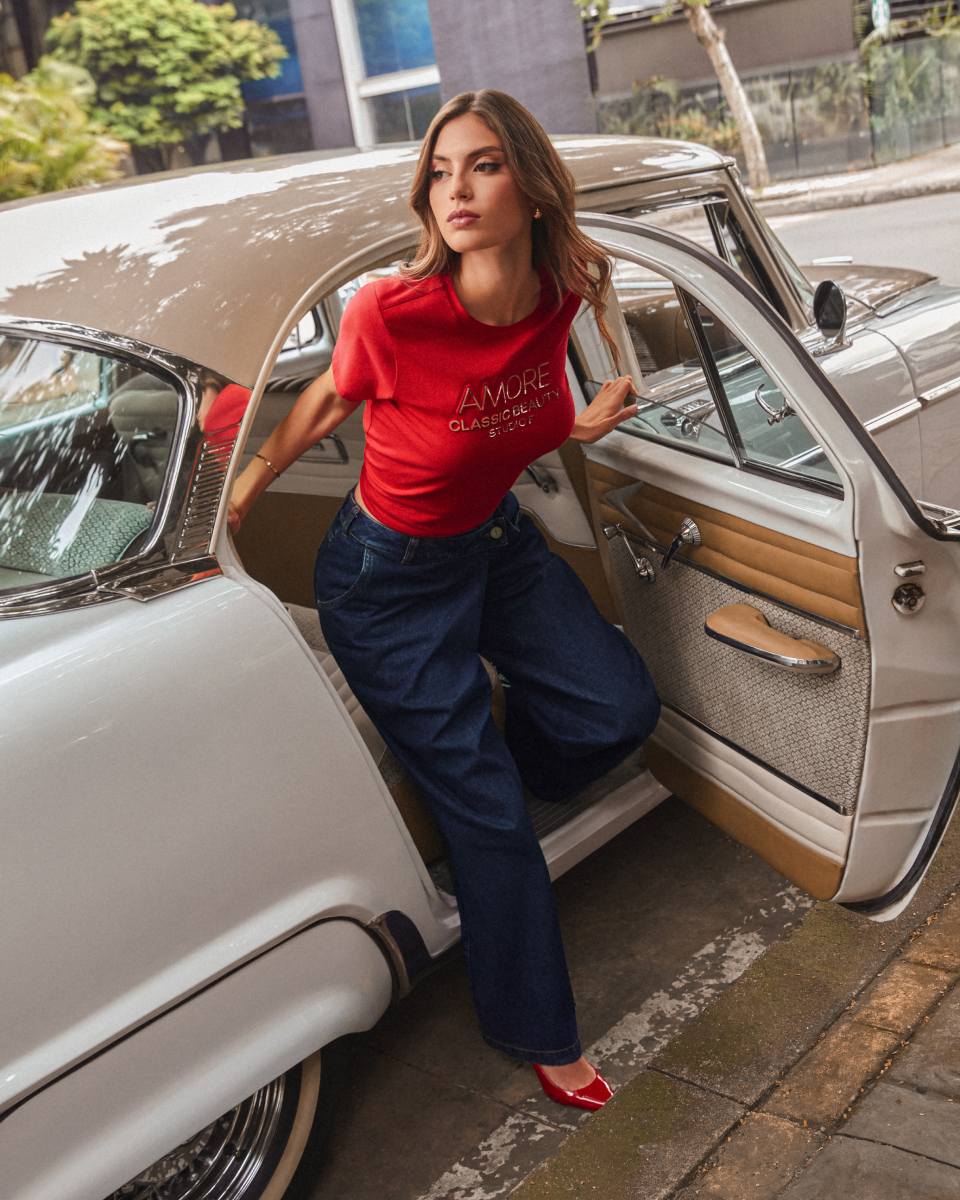 Modelo usando camiseta roja y jeans entrando a carro vintage, look casual romántico para cita de San Valentín.